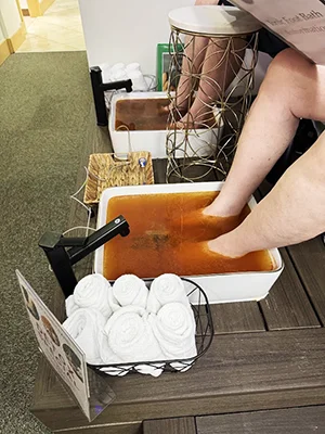 Patient soaking both feet in an orange-colored detox foot bath
