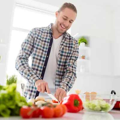 Smiling man chopping fresh vegetables while preparing a healthy meal