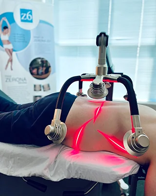 Patient receiving ZENORA laser therapy with red light across the abdomen